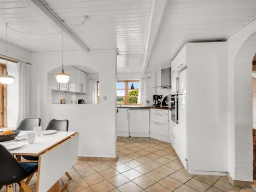 a kitchen and dining room with white cabinets and a table at Holiday Home Aliza - 300m to the fjord by Interhome in Roslev