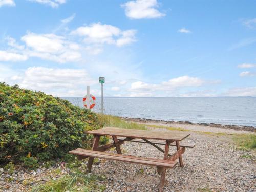 a wooden picnic table sitting on the beach at Holiday Home Eisa - 300m to the fjord by Interhome in Øsløs