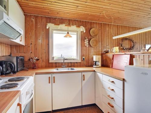 a kitchen with wooden walls and white cabinets and a sink at Holiday Home Pavo - 300m to the fjord by Interhome in Vinderup