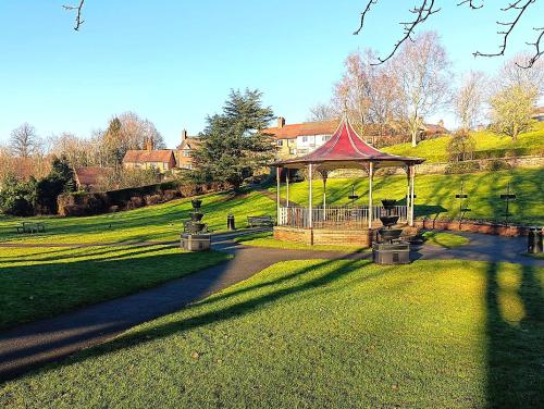 a gazebo with a red top in a park at The Whitchurch Apartment- The Painted Rooms in Whitchurch