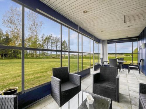 a screened porch with chairs and tables and windows at Holiday Home Mikkeline - 400m to the fjord by Interhome in Øster Assels