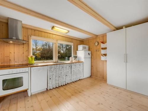 a kitchen with white appliances and wooden walls at Holiday Home Scarlet - 400m to the inlet by Interhome in Vinderup