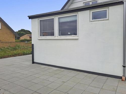 a white building with two windows and a patio at Holiday Home Thomsen - 200m to the inlet by Interhome in Sønder Dråby