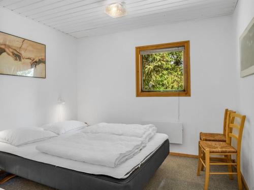 a bed in a room with a chair and a window at Holiday Home Anine - 200m to the fjord by Interhome in Højslev