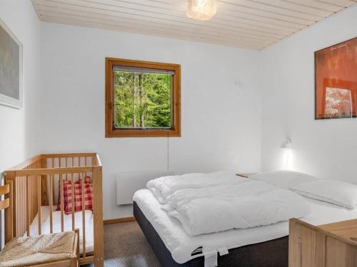 a bedroom with a bed and a window and a crib at Holiday Home Anine - 200m to the fjord by Interhome in Højslev