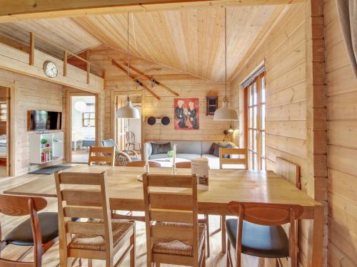 a dining room and kitchen with a wooden table and chairs at Holiday Home Kersta - 400m from the sea by Interhome in Rønde