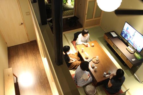 a group of people sitting in a living room playing a video game at 京一軒町家 さと居 鉄仙 SATOI TESSEN Omiya-Gojo in Kyoto