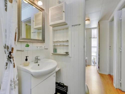 a white bathroom with a sink and a mirror at Holiday Home Deik - 2km to the fjord by Interhome in Vester Jølby