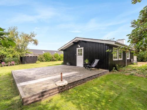 a black shed with a wooden deck in the yard at Holiday Home Suoma - 400m to the fjord by Interhome in Roslev