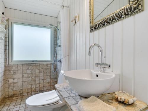 a bathroom with a sink and a toilet and a mirror at Holiday Home Suoma - 400m to the fjord by Interhome in Roslev