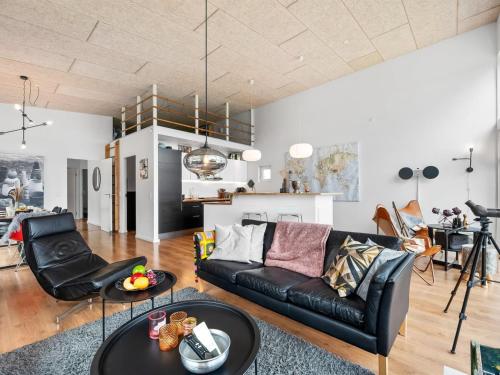 a living room with a black leather couch and a table at Holiday Home Tenna - 250m to the fjord by Interhome in Højslev