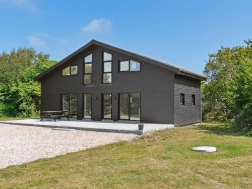 a black house with a bench in front of it at Holiday Home Markhild - 300m to the fjord by Interhome in Sønder Ydby