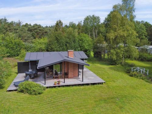a small house with a black roof in a field at Holiday Home Skjold - 600m from the sea by Interhome in Grenå