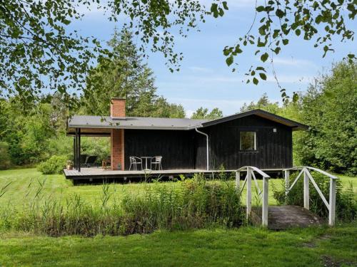 a black cabin with a deck in a field at Holiday Home Skjold - 600m from the sea by Interhome in Grenå