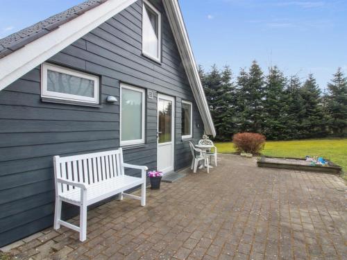 a blue house with a bench on a brick patio at Holiday Home Ellenor - 300m to the inlet by Interhome in Højslev