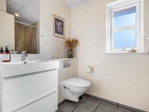 a white bathroom with a toilet and a sink at Holiday Home Alrike - 850m from the sea by Interhome in Brøndstrup