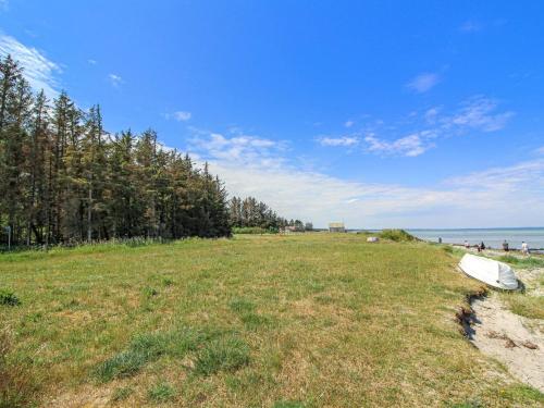 a surfboard laying on the grass next to a beach at Holiday Home Ernestina - 500m from the sea by Interhome in Glesborg