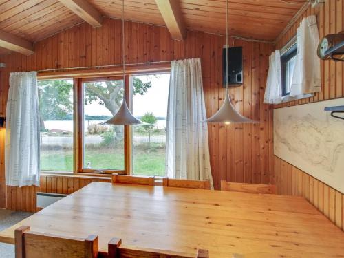 a dining room with a wooden table and a large window at Holiday Home Graa by Interhome in Skanderborg