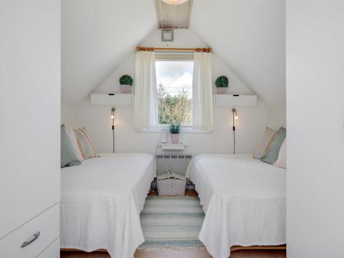 two beds in a attic room with a window at Holiday Home Botwith - 400m from the sea by Interhome in Ørsted