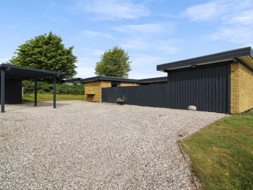 a house with a gravel driveway in front of a building at Holiday Home Kiowa - 100m from the sea by Interhome in Allingåbro