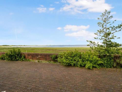 a brick wall with a tree and some bushes at Holiday Home Emmie - 50m to the fjord by Interhome in Skarum