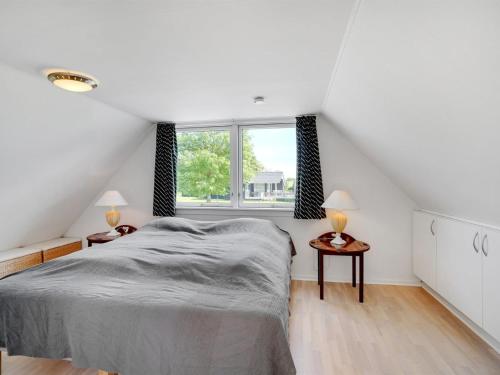 a white bedroom with a bed and a window at Holiday Home Edvia - 700m to the fjord by Interhome in Løgstrup