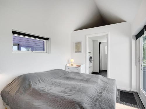 a white bedroom with a bed and a window at Holiday Home Edvia - 700m to the fjord by Interhome in Løgstrup