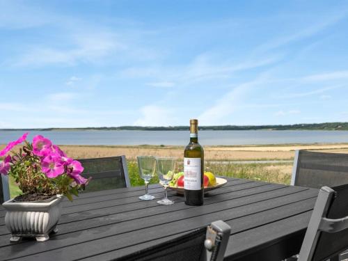 a bottle of wine sitting on a wooden table with glasses at Holiday Home Ephra - 250m to the fjord by Interhome in Roslev