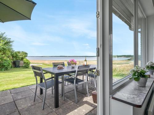 a table and chairs on a patio with a view of the ocean at Holiday Home Ephra - 250m to the fjord by Interhome in Roslev