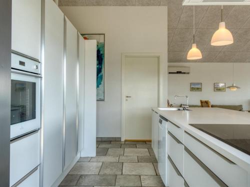 a kitchen with white cabinets and a sink at Holiday Home Elissa - 50m to the fjord by Interhome in Roslev