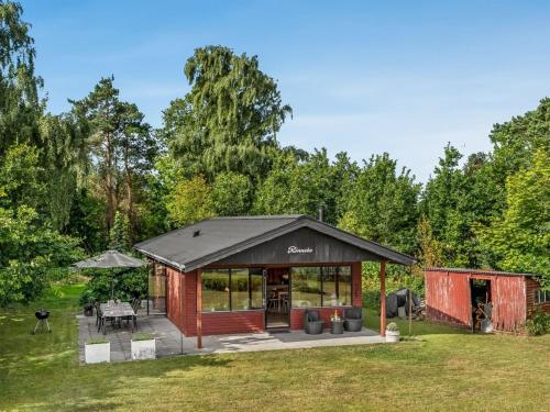 a cabin with a black roof in a field at Holiday Home Tayana - 75m to the inlet by Interhome in Storvorde