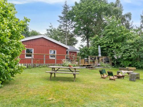 a picnic table and chairs in a yard with a red barn at Holiday Home Reika - 1km from the sea by Interhome in Glesborg