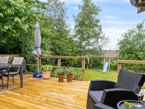 a wooden deck with an umbrella and a table and chairs at Holiday Home Reika - 1km from the sea by Interhome in Glesborg