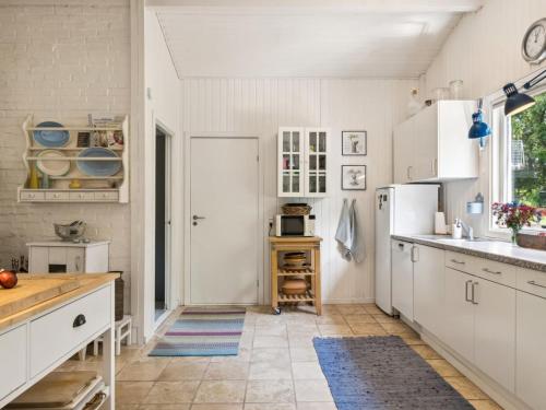 a kitchen with white cabinets and a white refrigerator at Holiday Home Reika - 1km from the sea by Interhome in Glesborg