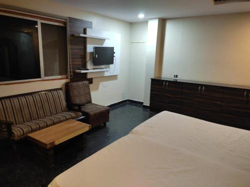 a hotel room with a bed and a couch and a tv at HoTEL ABHIRAM PALACE in Vijayawāda