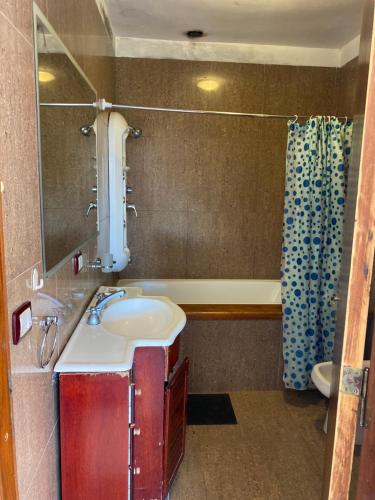 a bathroom with a sink and a mirror and a tub at Ohana Apartments (solo familias) in Villa Carlos Paz