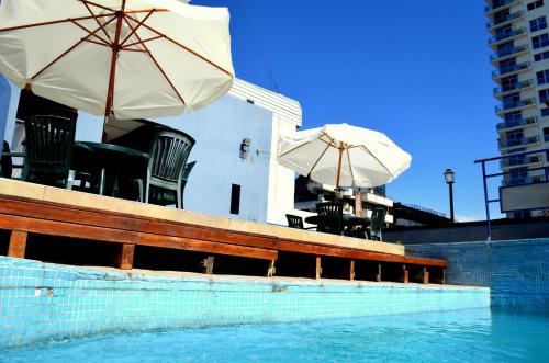 a pool with chairs and umbrellas next to a building at San lorenzo apart in Mendoza