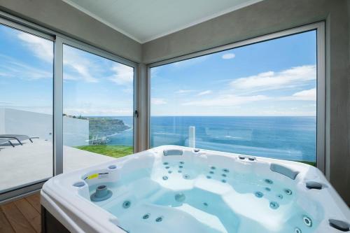 a bath tub in a room with a view of the ocean at Beira Da Rocha in Ponta Delgada