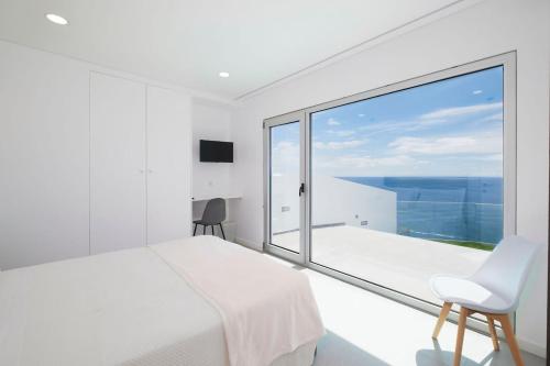 a bedroom with a white bed and a large window at Beira Da Rocha in Ponta Delgada