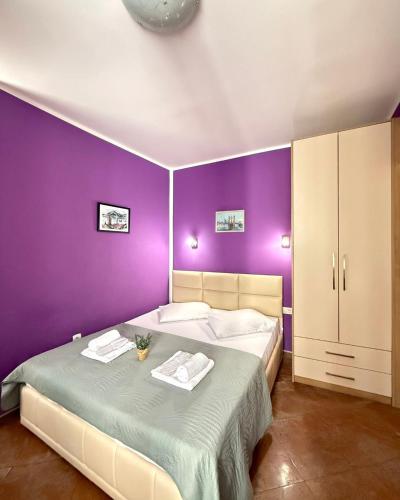 a purple bedroom with a bed with two towels on it at Apartments Casa del Sol Jovana in Kotor