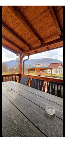 a wooden table on a deck with chairs on a balcony at Casa Edy in Vişeu de Sus
