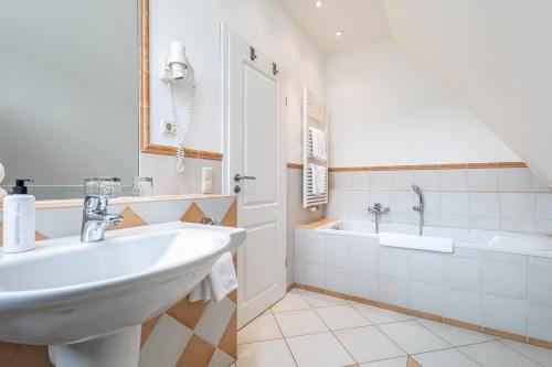 un bagno bianco con lavandino e vasca di Dünentraum a Neuhaus