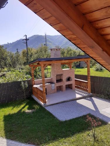 a brick fireplace under a wooden gazebo at Casa Edy in Vişeu de Sus