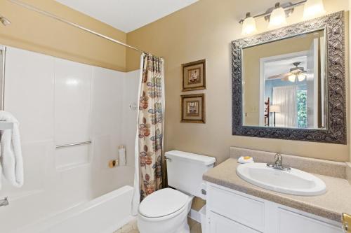 Un baño con un inodoro, un lavabo y un espejo. en Peach Seashell, en Destin