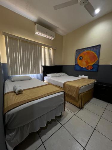 a room with two beds and a painting on the wall at Hotel Plaza Cosiguina in Chinandega