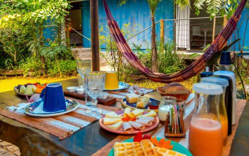 a picnic table with food and drinks and a hammock at Pousada Container Eco Manguinhos in Manguinhos