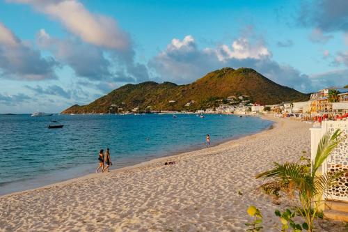 a beach with people walking on the sand and the water at Suite 7 Mogador Residence, 1BR, brand-new, rare & luxury, beachfront in Grand Case
