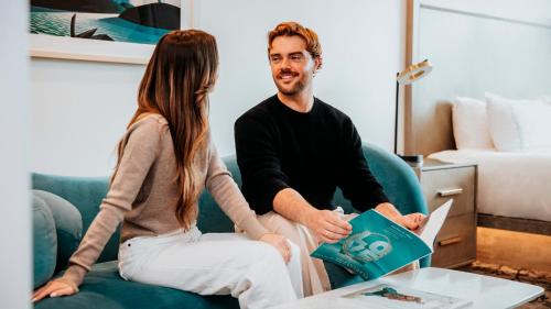 a man and woman sitting on a couch in a hotel room at The Parker Hotel and Rooftop in Vancouver
