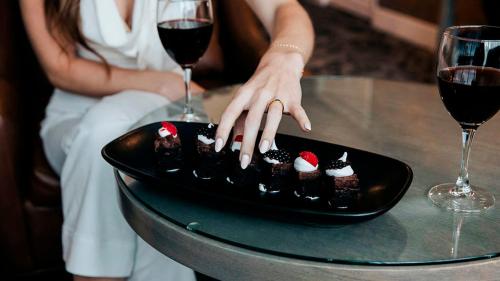 a woman sitting at a table with a plate of desserts at The Parker Hotel and Rooftop in Vancouver