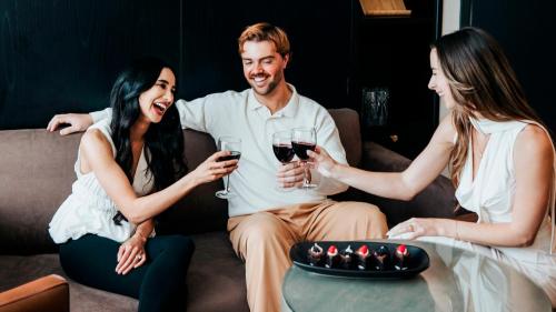 a group of three people sitting on a couch drinking wine at The Parker Hotel and Rooftop in Vancouver